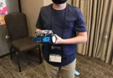Child holding small STEM robot, wearing face mask